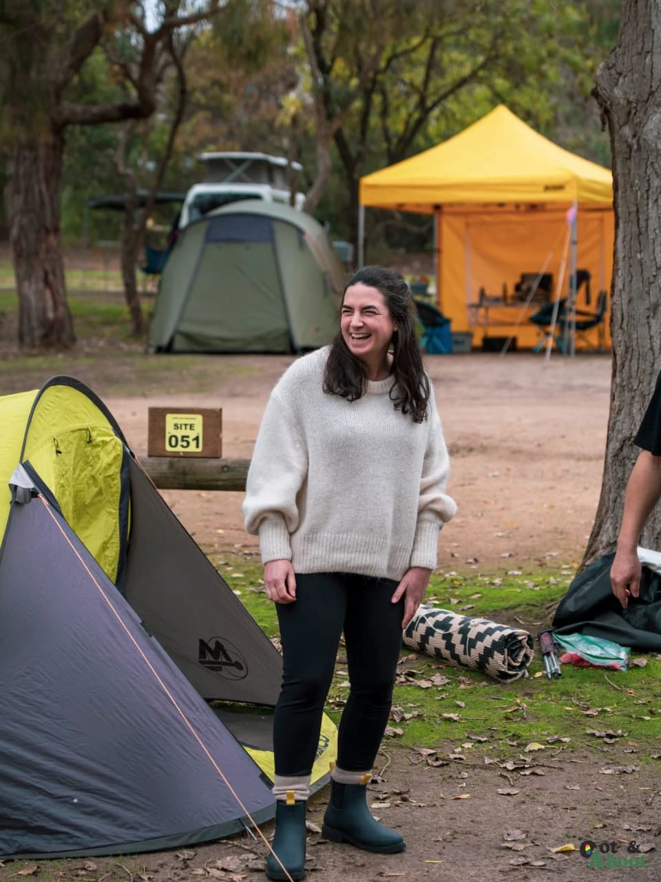 A camper smiling next to a tent